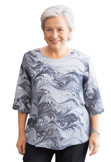 Woman wearing a marbled silk half sleeve top in black and white  and black pants standing against a white background.