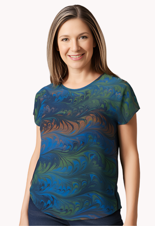 Woman wearing a gray, blue and peach marbled silk shirt against a white background
