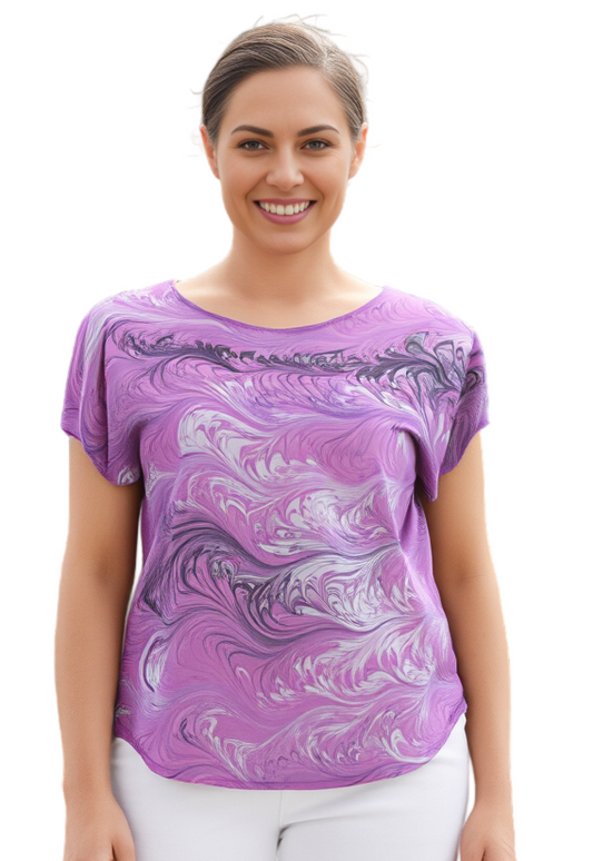 Woman wearing a soft pink, white and black marbled shirt and white pants on a white background