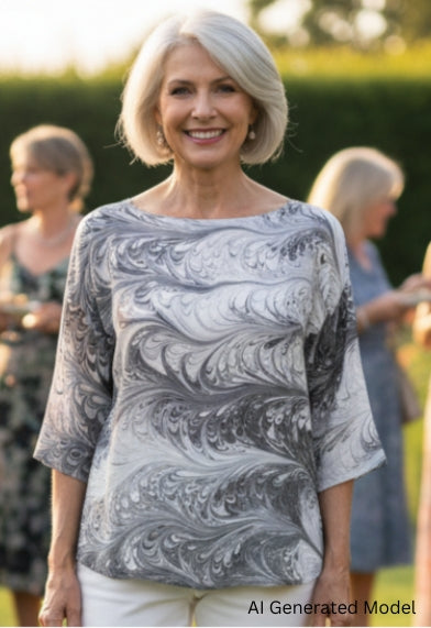 Woman wearing a black and white marbled silk top standing in a garden with people in the background