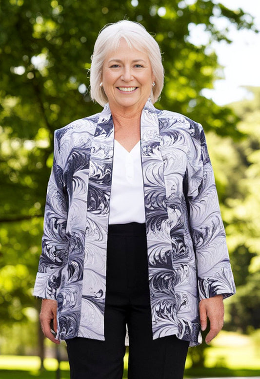 Woman wearing a marbled silk jacket in black and white outdoors with greenery in the background