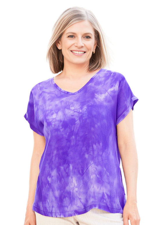 Woman wearing a soft violet silk tie-dye shirt on a white background