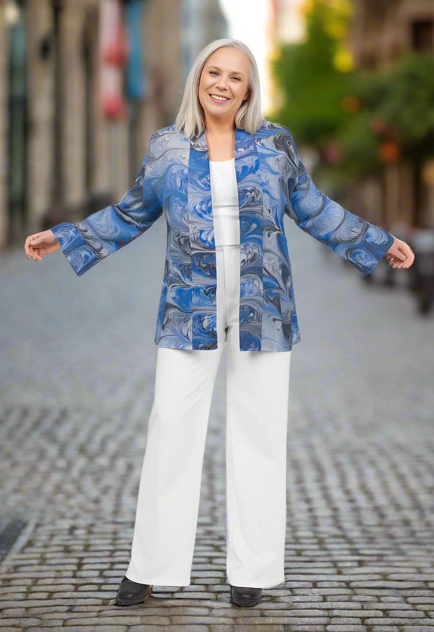 Woman wearing a blue marbled silk jacket and white pants on a white background