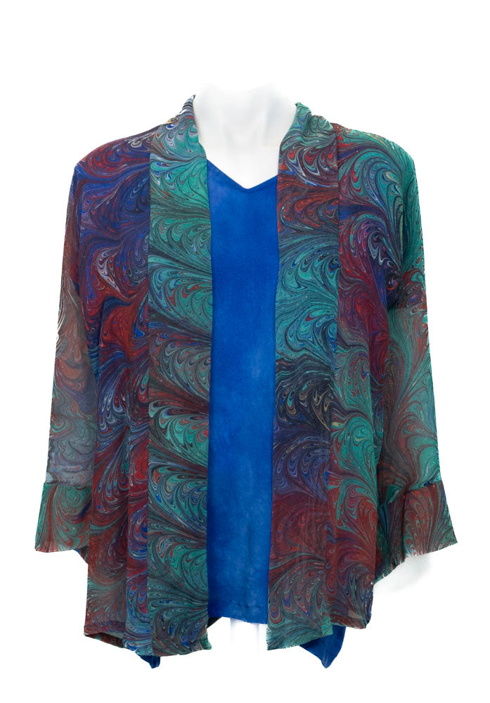 Colorful marbled silk sheer jacket over a blue top on a white background