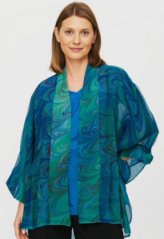 Woman wearing a blue and green marbled silk jacket against a white background