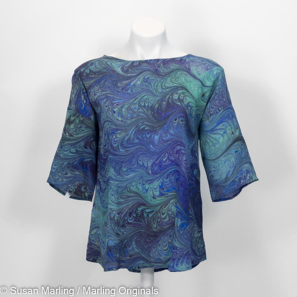 Blue and green marbled silk blouse on a mannequin against a white background
