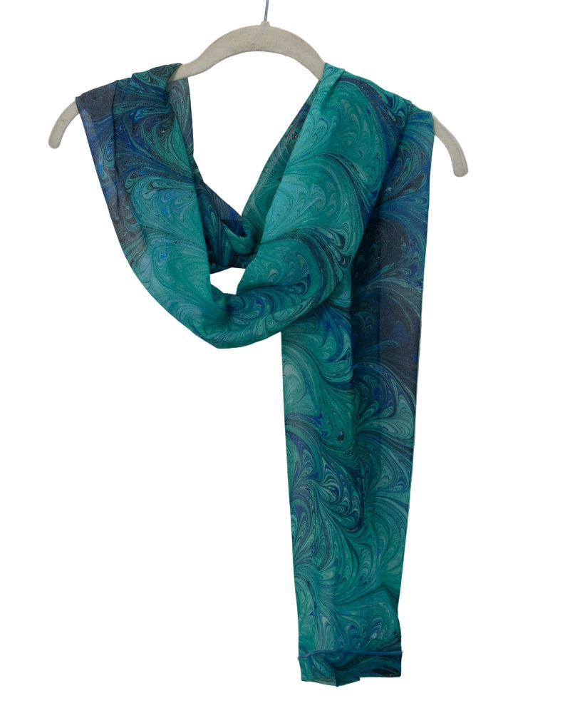 Blue and green marbled silk scarf on a hanger against a white background