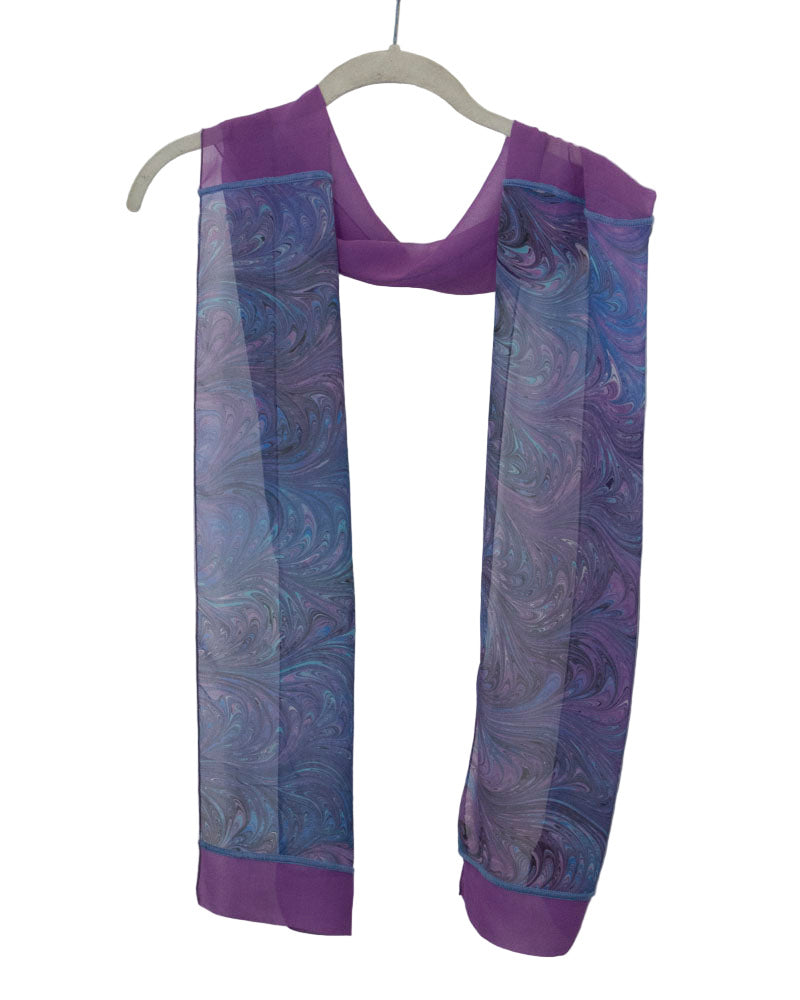 Purple and blue marbled silk scarf on a hanger against a white background