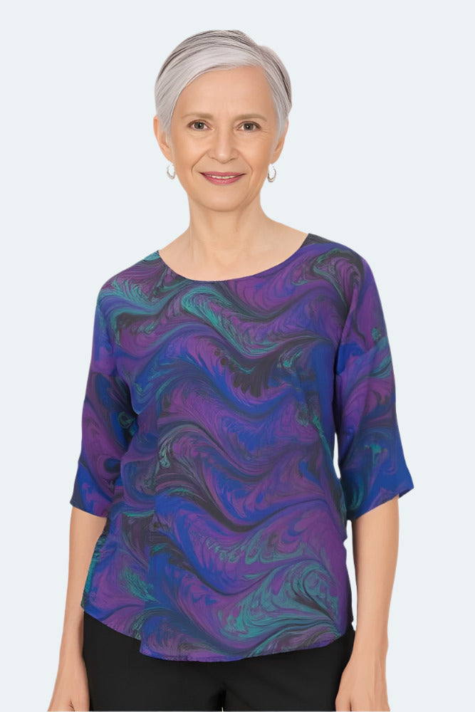 Woman wearing a jewel tone marbled silk blouse Against a white background